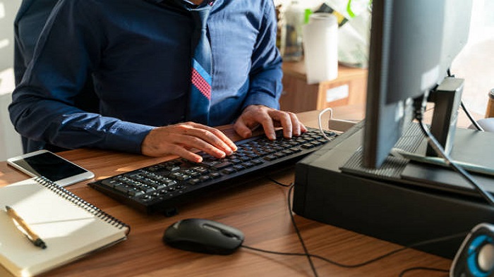 un homme tapant sur le clavier d'un ordinateur sur son bureau - portage salarial à Maurice -Activ Solution