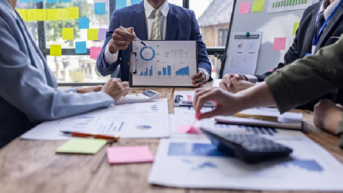 Un groupe d'hommes d'affaires confiants consultent des graphiques et des tableaux pour analyser les données du marché - gestionnaire de paie français - Activ Solution