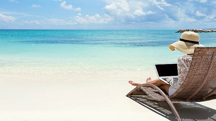 une femme travaillant avec son laptop sur la plage - télétravail à domicile - Activ Solution