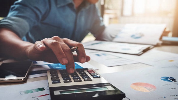 homme d'affaires utilisant une calculatrice avec un ordinateur portable - gestion de paie offshore à Maurice - Activ Solution