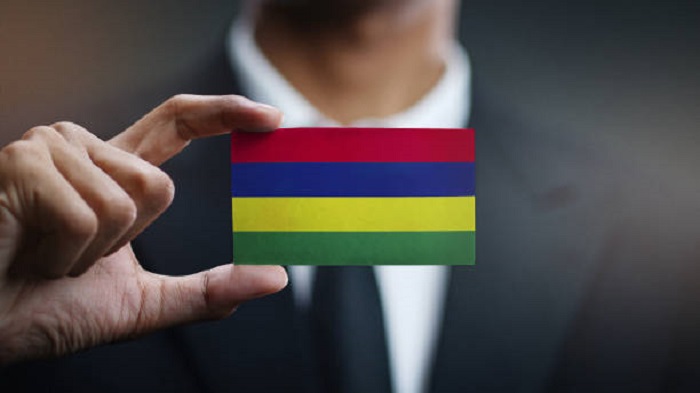Homme d'affaires tenant une carte du drapeau mauricien - stratégie externalisation de services - Activ Solution